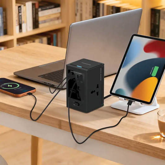 Black cube charging station powering laptop tablet and smartphone on home office desk