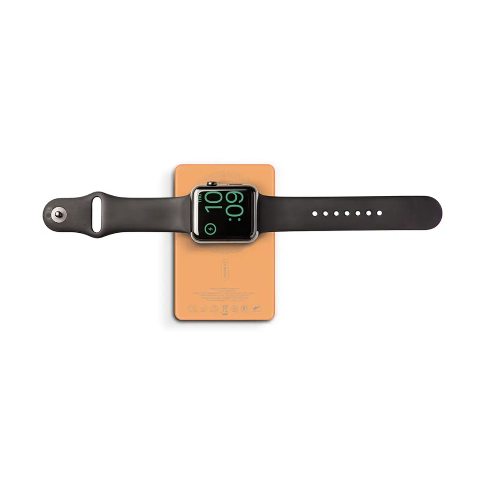 Orange power bank with black smartwatch resting on top displaying green charging icon