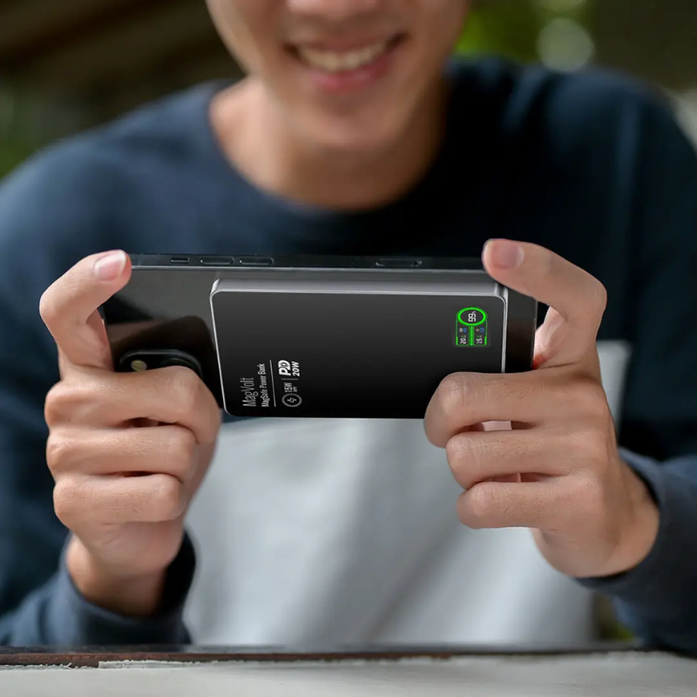 Black MagVolt magnetic power bank attached to smartphone with green TFT display showing 20W charging