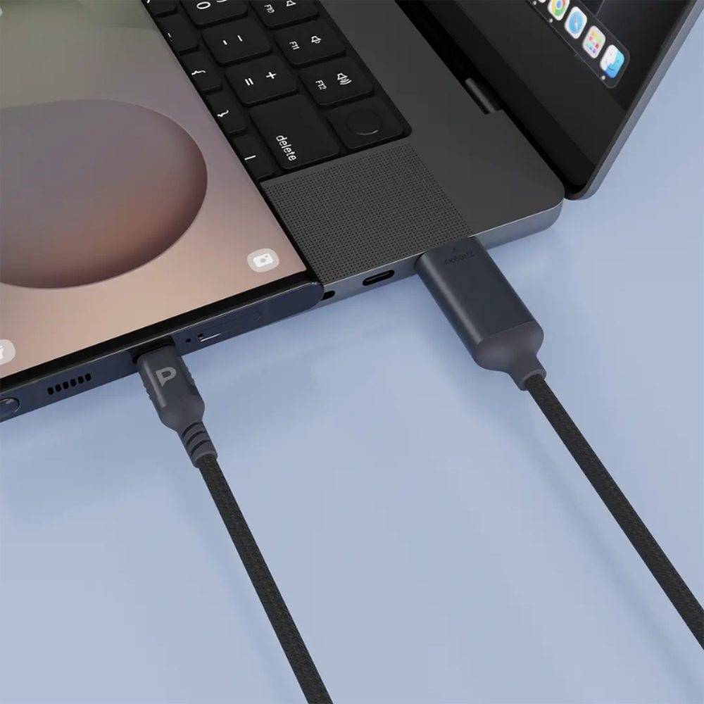 Close-up of black braided USB-C to HDMI adapter plugged into laptop and phone