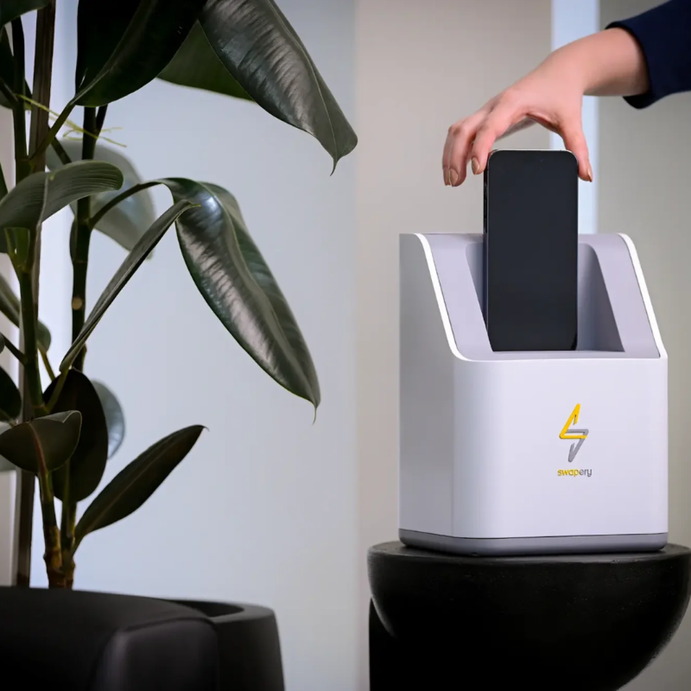 Person inserting smartphone into Swapery auto-swappable charging station