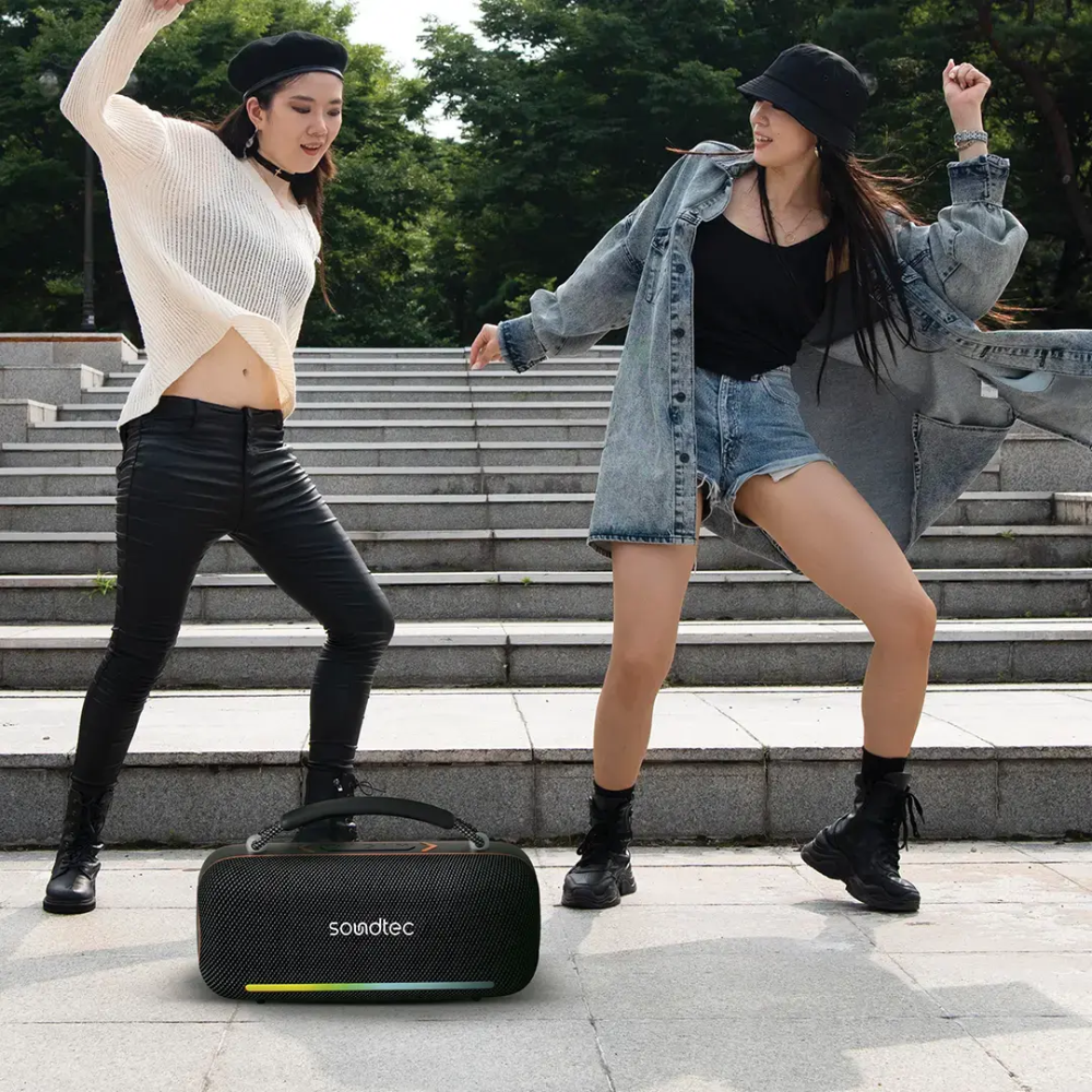 Outdoor party scene with black Soundtec wireless speaker on stone steps