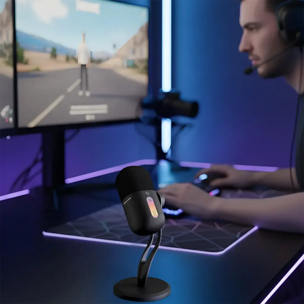 Black Porodo microphone on desk with gamer using headset and dual monitors