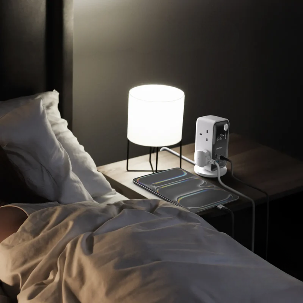 Momax 70W GaN power tower with digital display charging smartphone on nightstand