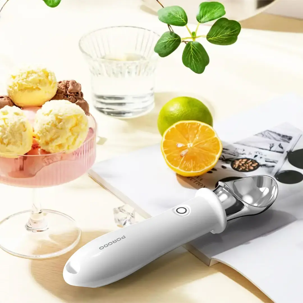 Porodo heated ice cream scoop resting on book next to fresh fruit for summer dessert serving