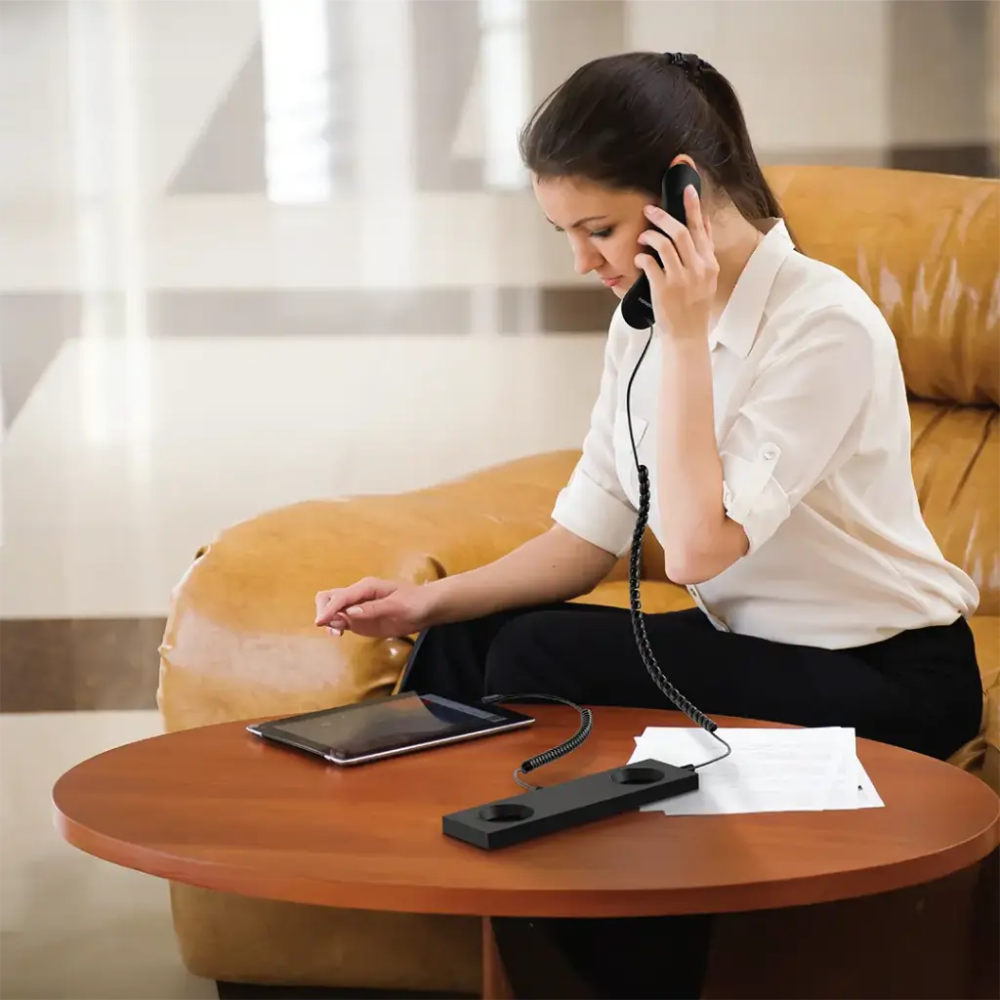 Woman using black Porodo retro telephone for clear calls in home office setting