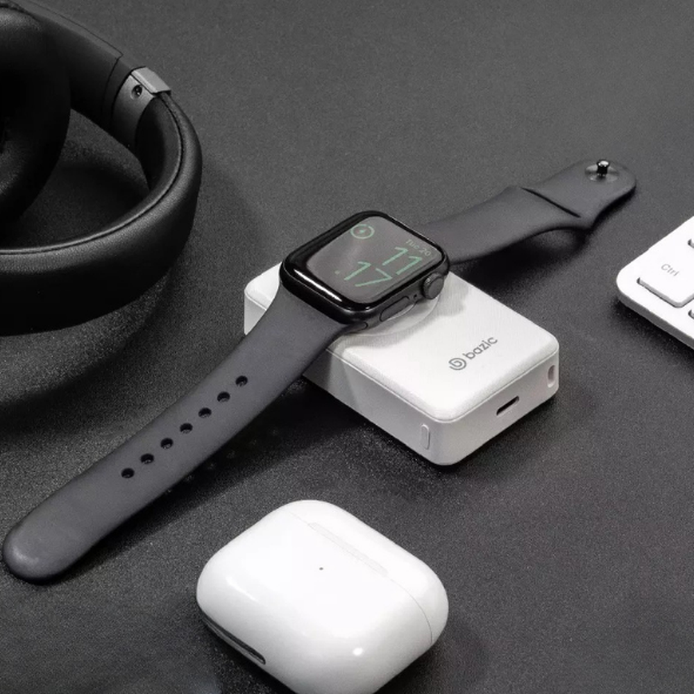 White Bazic 4000mAh power bank charging Apple Watch on wireless pad with headphones