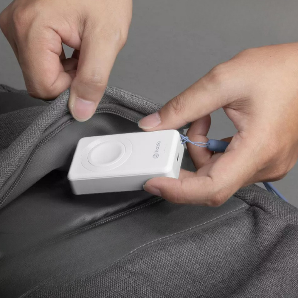 Bazic Mini 2-in-1 Power Bank with Apple Watch charger and lanyard held near backpack