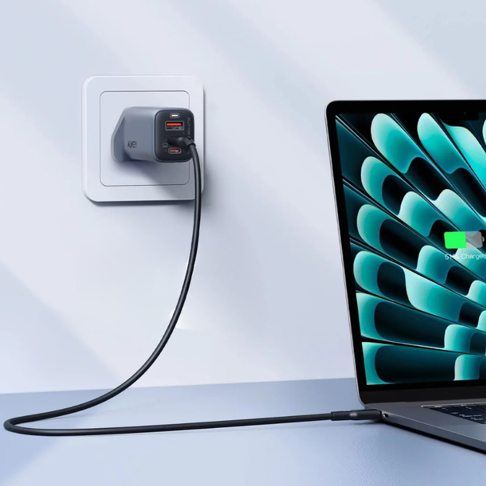 Aukey 67W GaN III wall charger charging laptop via USB-C with orange-accented ports