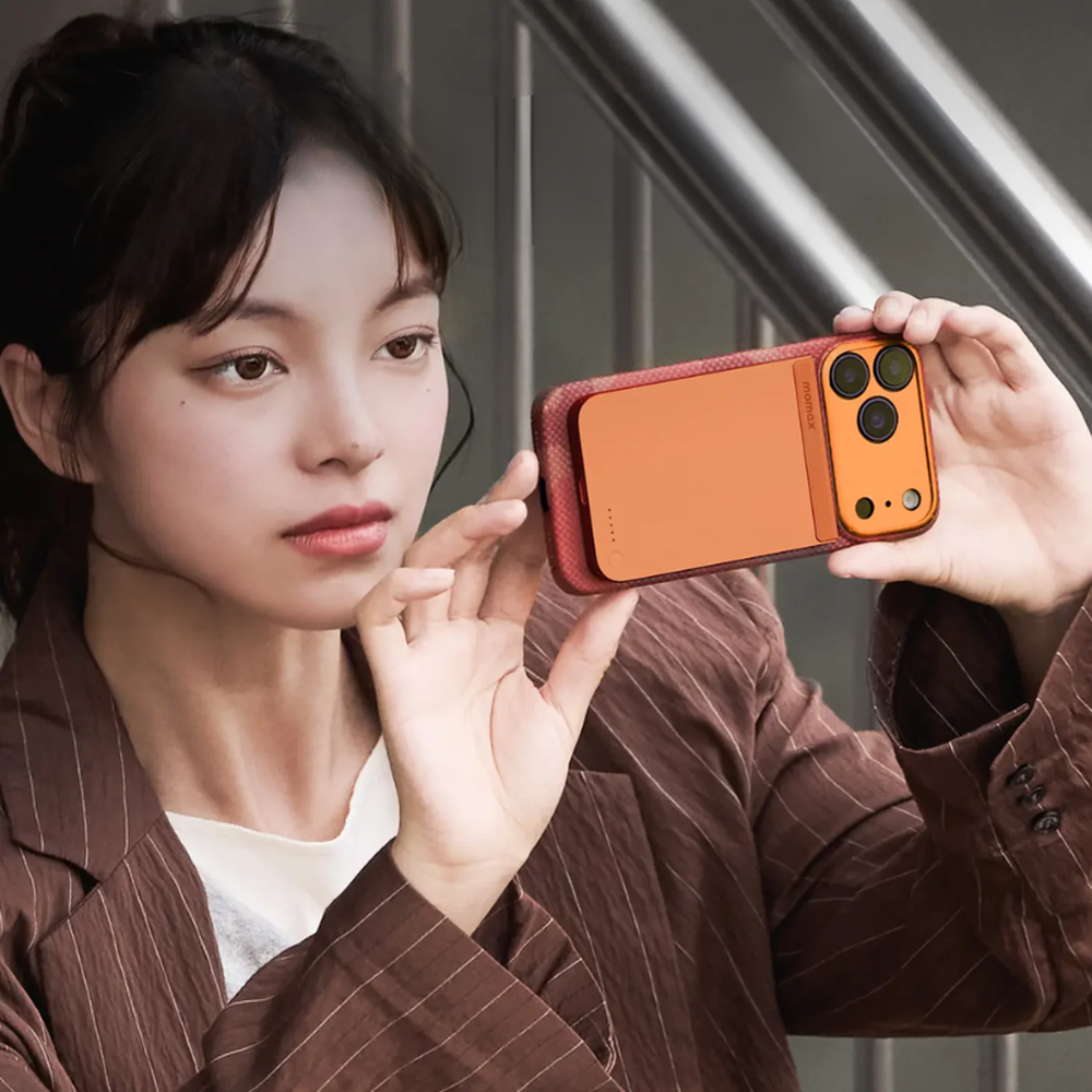 Woman holding smartphone with orange textured Momax power bank