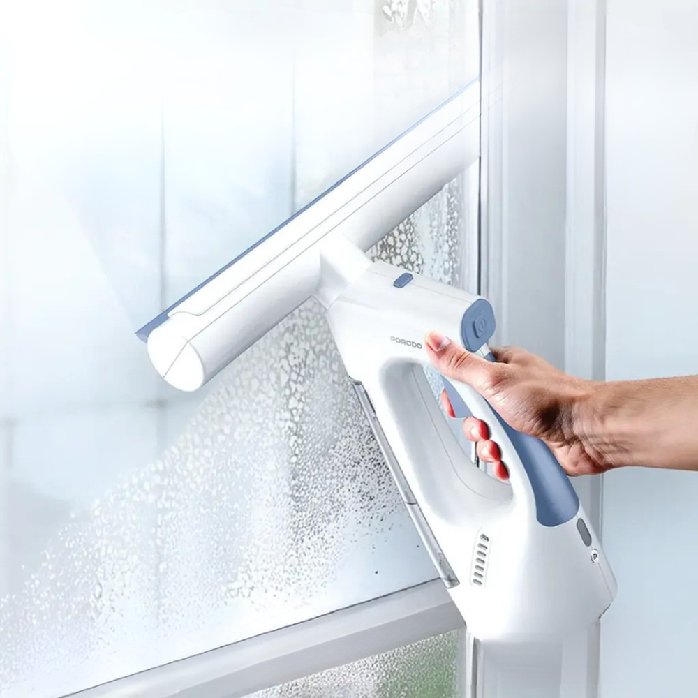 Hand holding Porodo spray wipe vacuum cleaner on glass surface with foam droplets