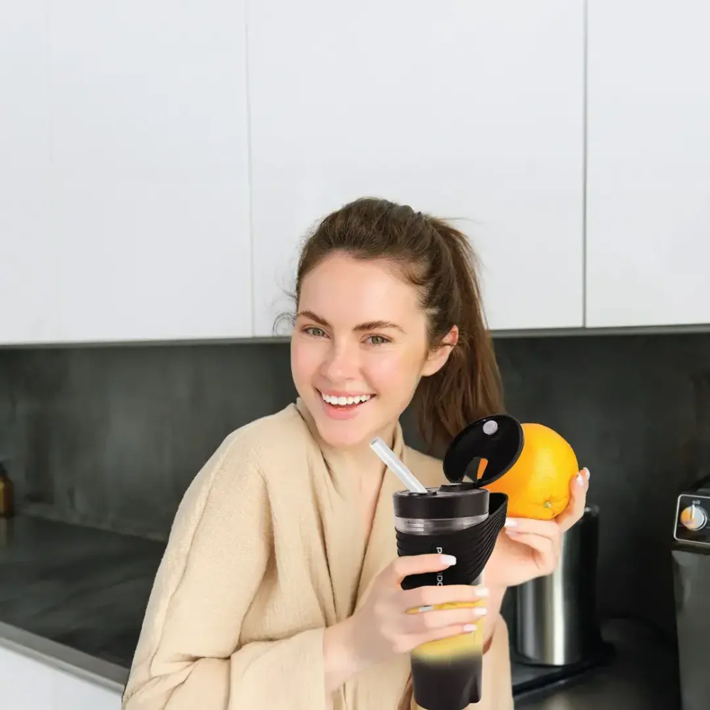 Woman holding black Porodo portable blender with orange in modern kitchen