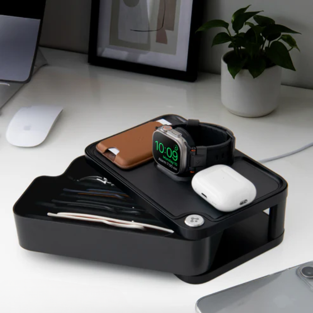 Black Apple Watch charging desk organizer holding watch AirPods and wallet on white surface