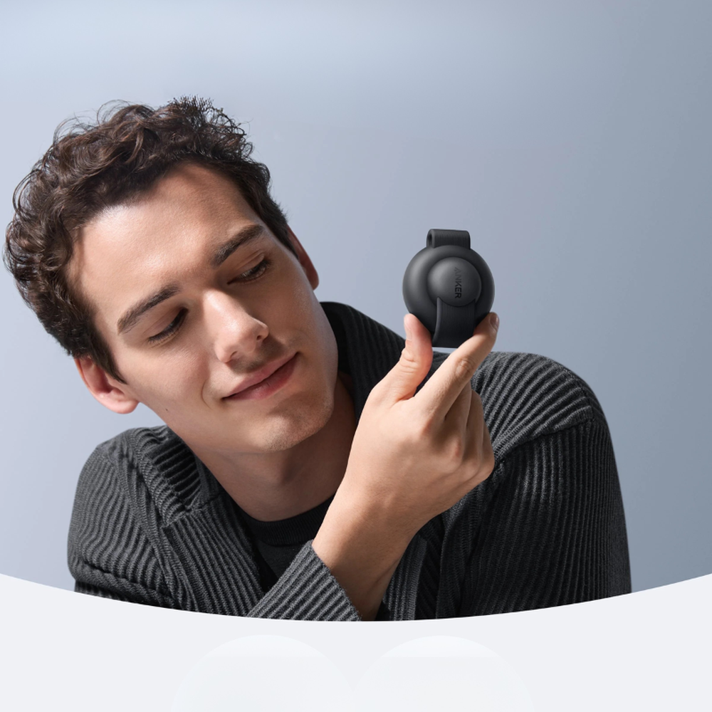 Man holding compact black Anker portable wireless charging station with embossed logo