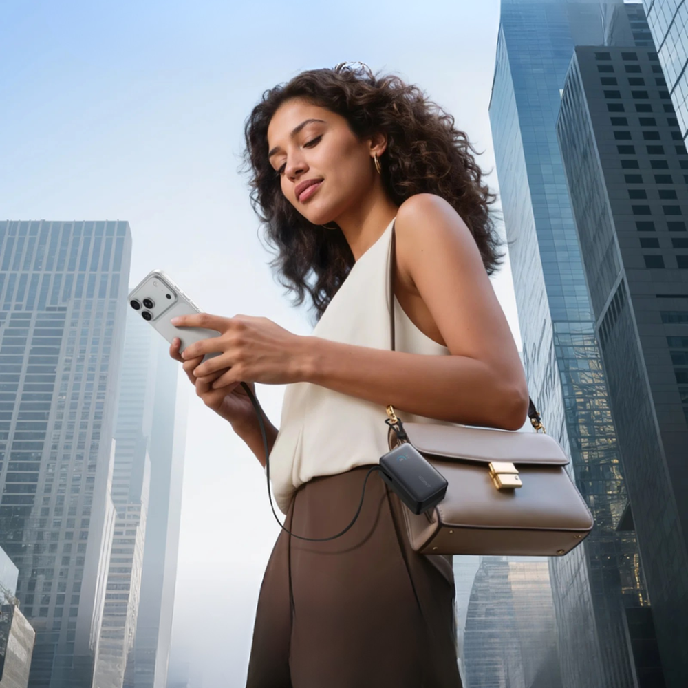 Urban commuter using Anker power bank attached to handbag for travel