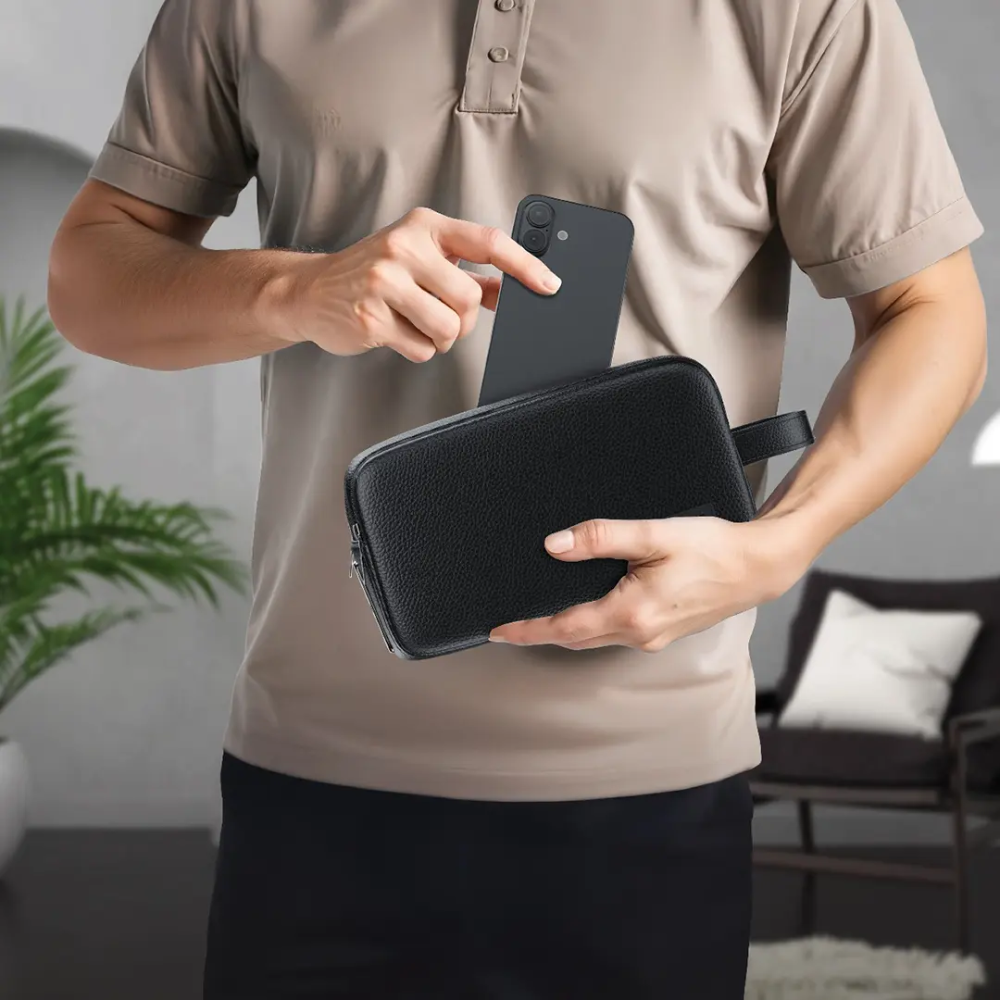 Person holding black Lyon fingerprint bag while inserting smartphone into front pocket