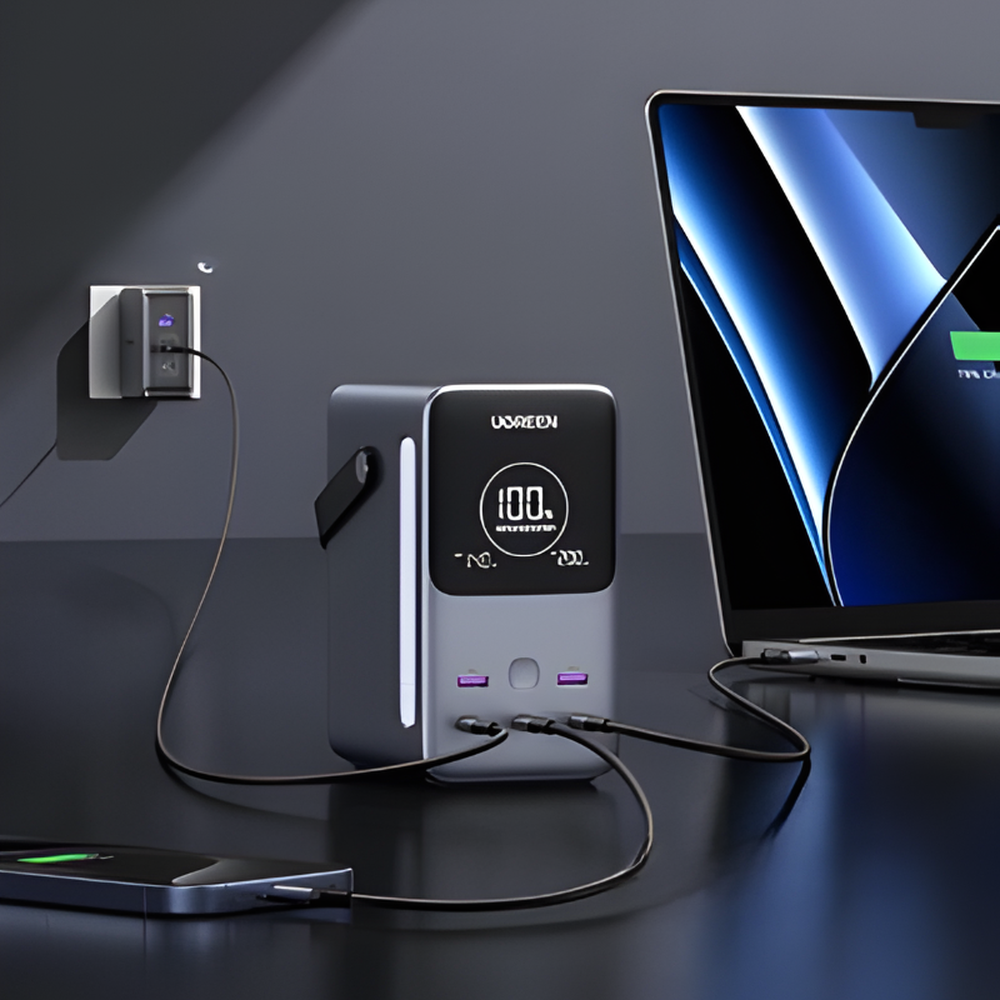 Gray Ugreen power bank charging laptop and smartphone via USB-C ports with digital screen