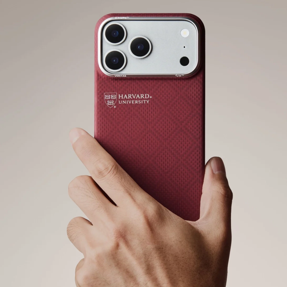Hand holding maroon Harvard University shield logo phone case