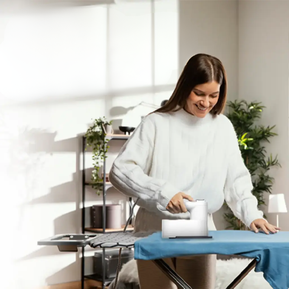 Woman using white cordless steam iron on blue fabric for wrinkle removal