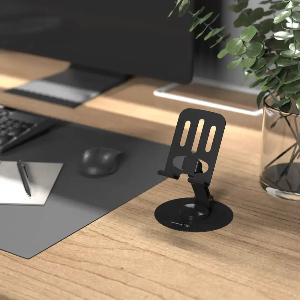 Foldable black phone stand on desk next to monitor showcasing ergonomic arm support