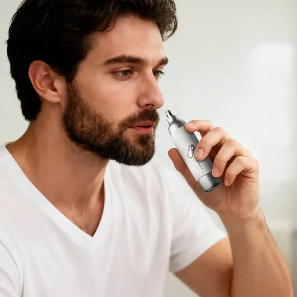 Man using silver Porodo electric shaver for nose hair trimming in bathroom