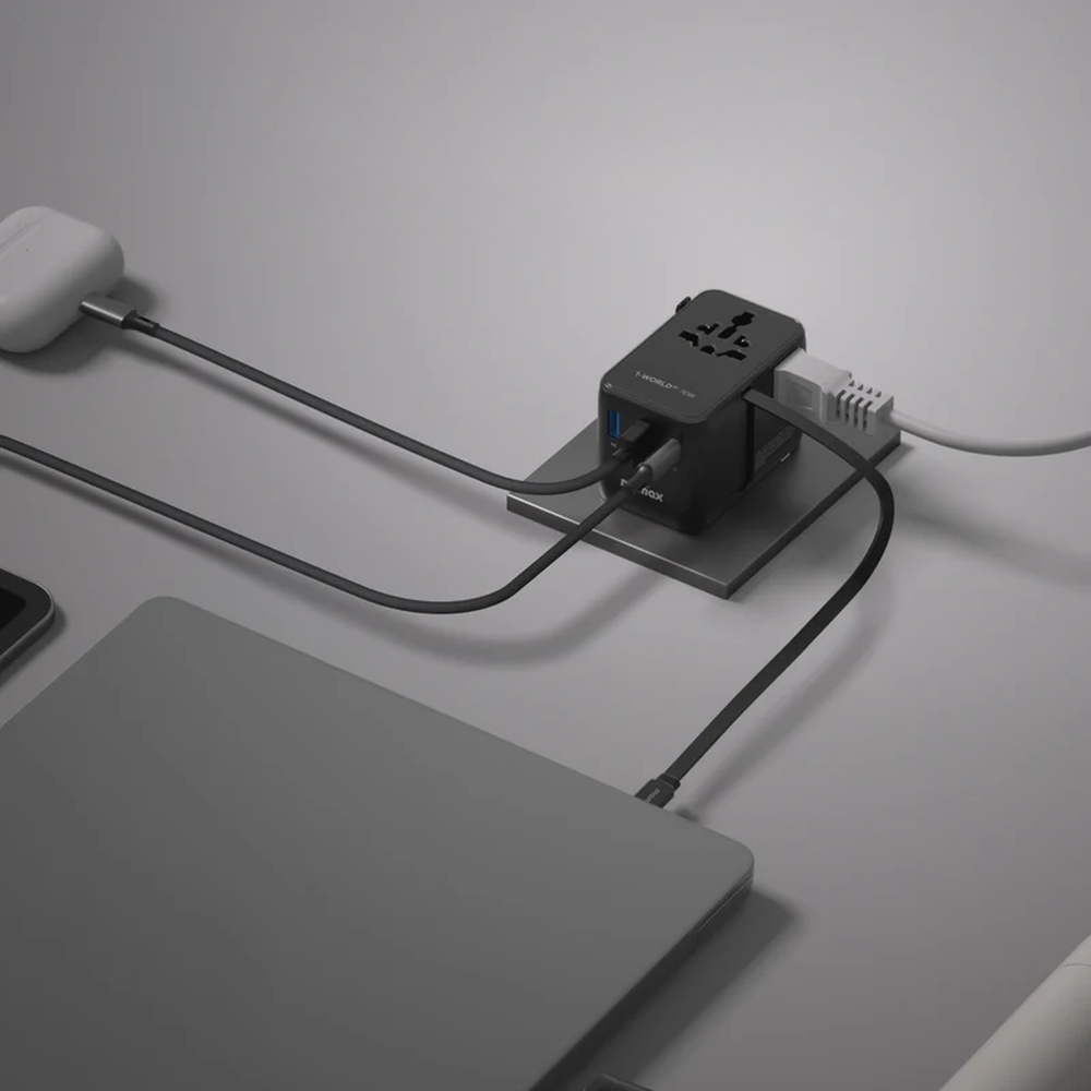 Momax 3-port travel adapter charging laptop and earbuds on desk