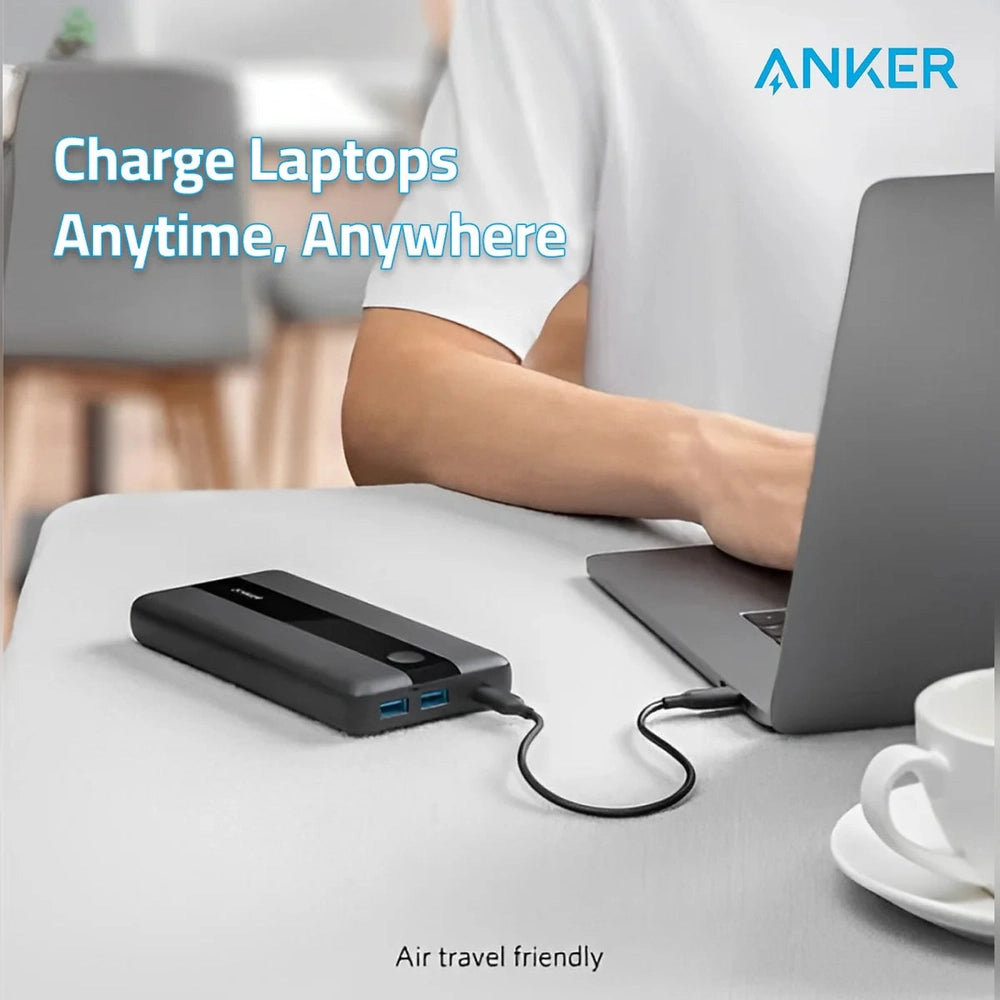 Person using Anker 60W portable charger to power silver laptop during travel