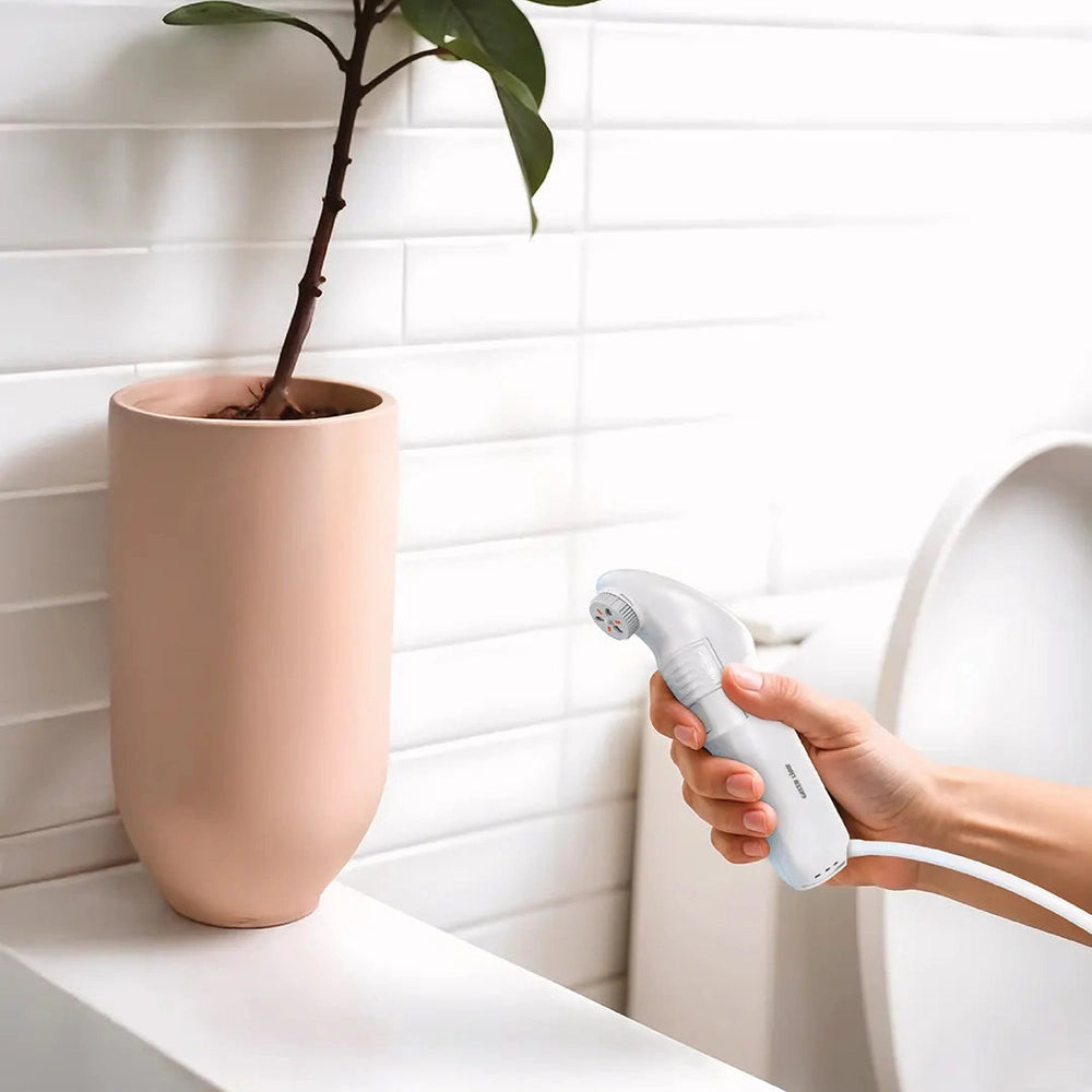 Handheld white travel bidet in bathroom showing compact ergonomic grip