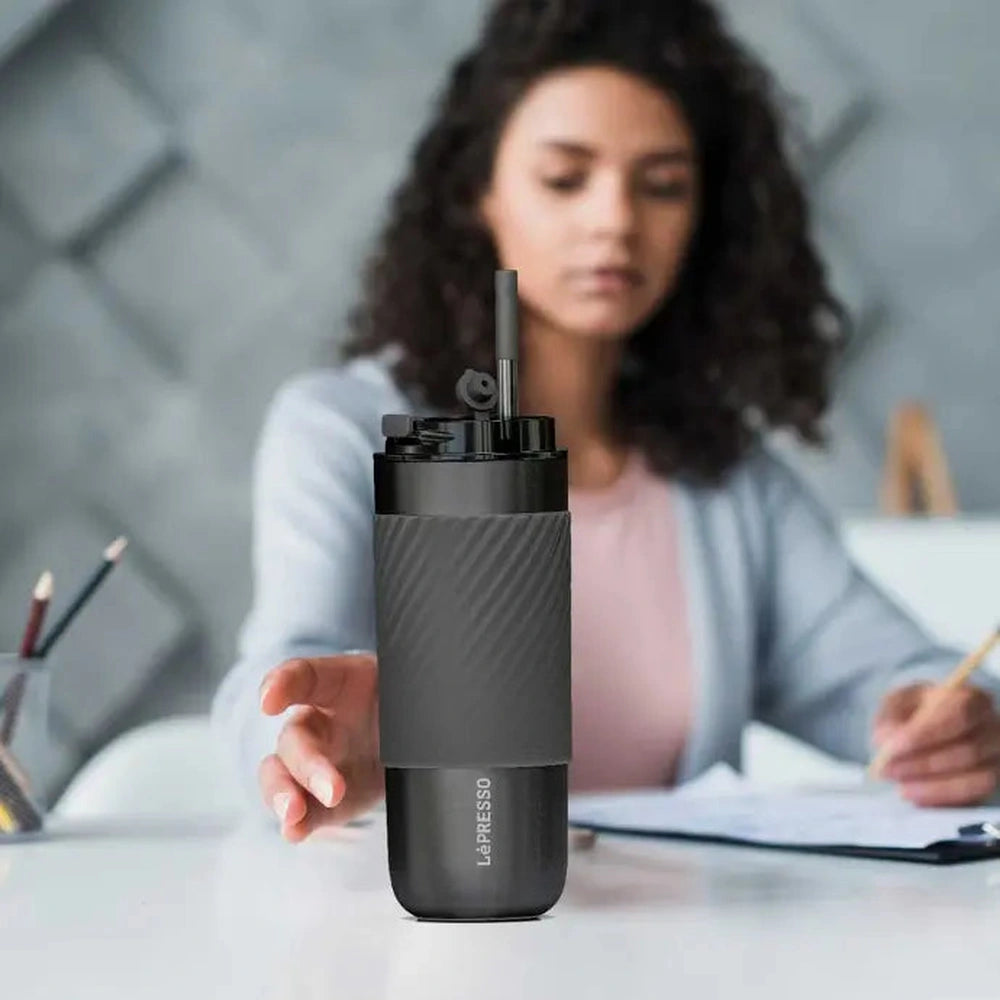 Black Lepresso travel mug on office desk with reusable straw