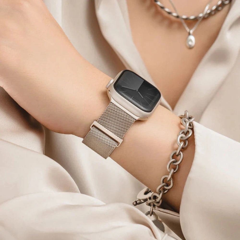 Silver mesh watch band worn on wrist with white blouse and jewelry