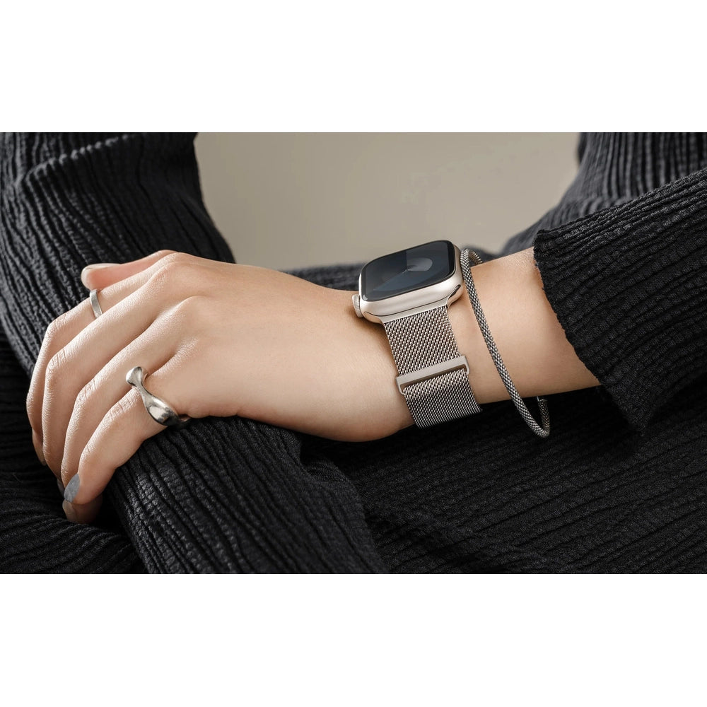 Silver mesh watch band styled on wrist with ribbed sweater and rings