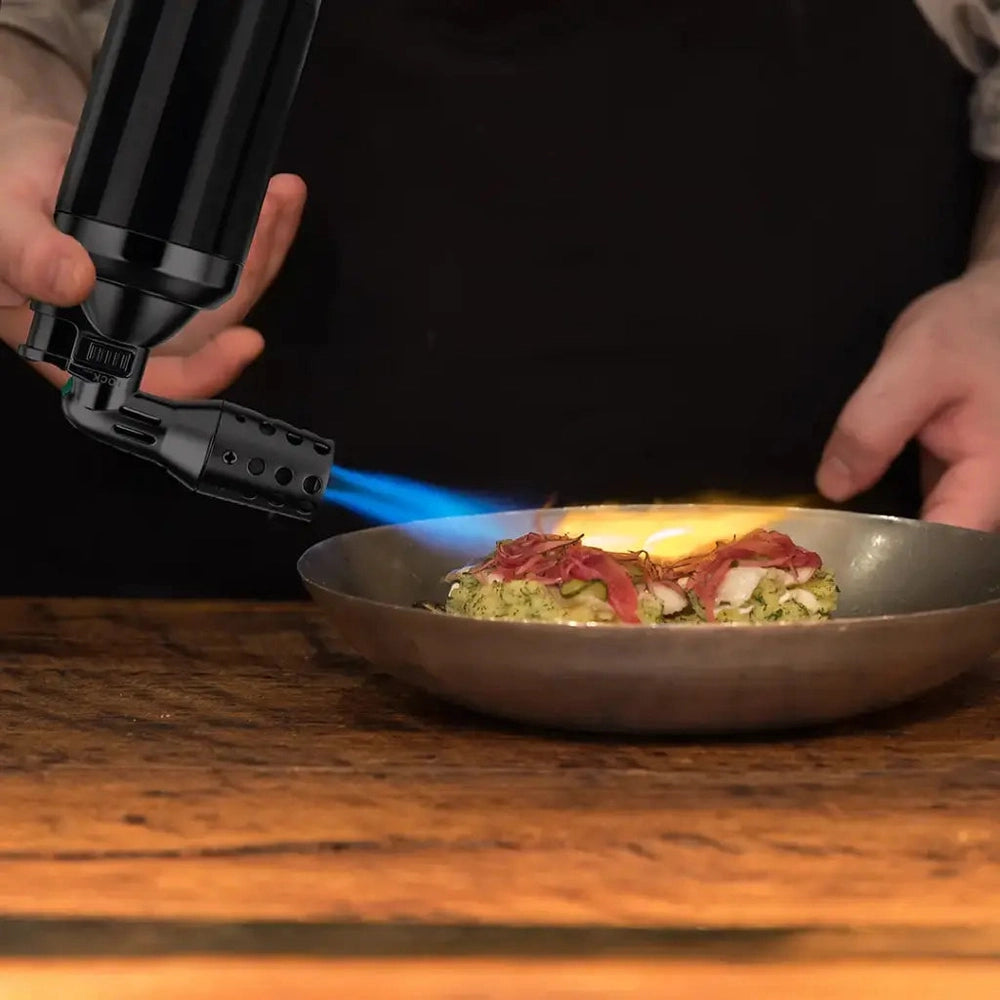 Using black turbo flame torch to sear food in metal pan with blue jet fire