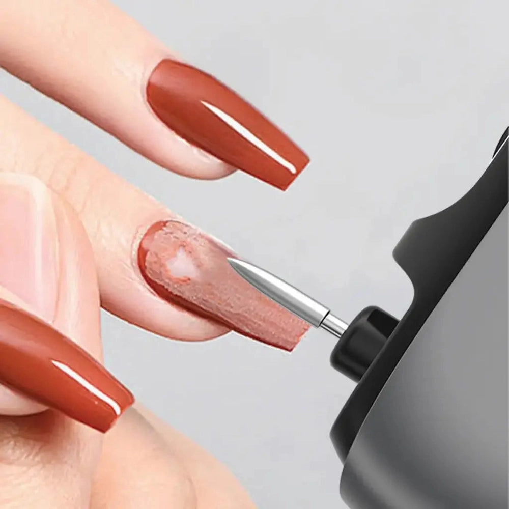 Black electric nail clipper actively removing old polish from glossy brown nails