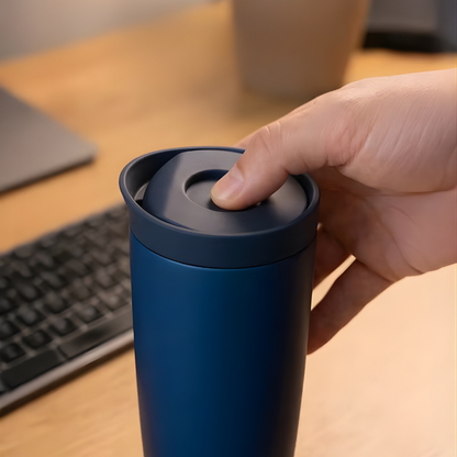 Hand pressing Brave navy blue travel mug lid at office desk